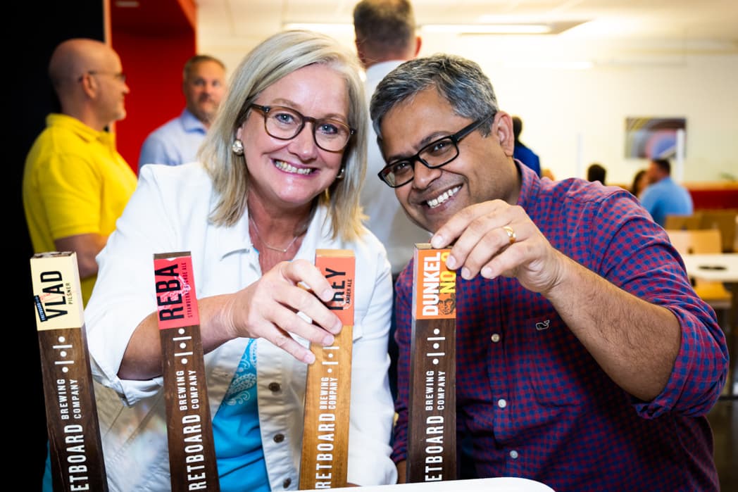 Two colleagues holding craft beer tap handles and smiling at company networking event — Cincinnati event photographer K Dalton