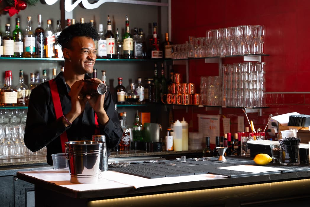Bartender smiling while shaking cocktail behind bar at corporate holiday event — Cincinnati event photographer K Dalton
