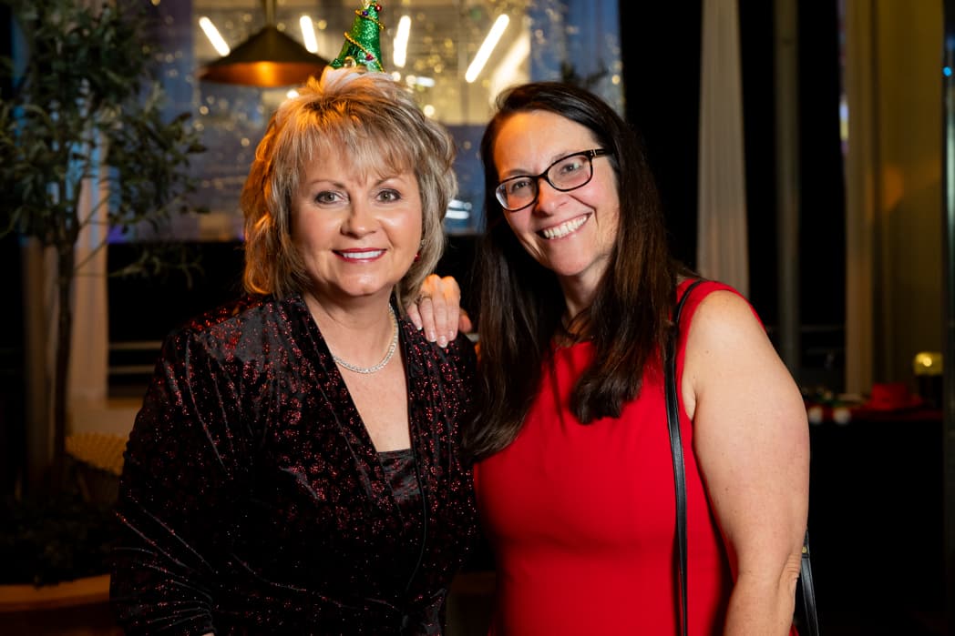Two women posing together at holiday party in festive attire — Cincinnati event photographer K Dalton