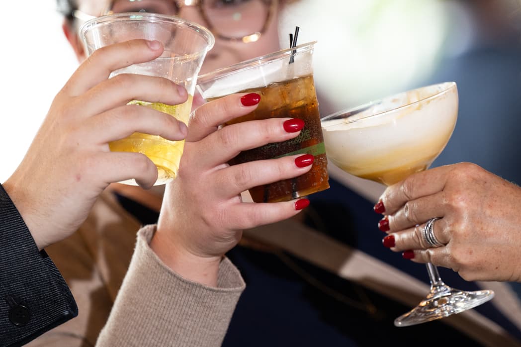 Three hands raising cocktail glasses in a toast at corporate event — Cincinnati event photographer K Dalton