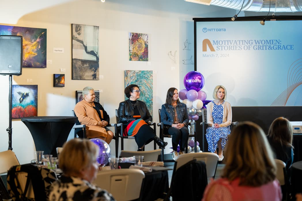 Four women panelists seated on stage at NTT Data Motivating Women event in art gallery venue — Cincinnati event photographer K Dalton