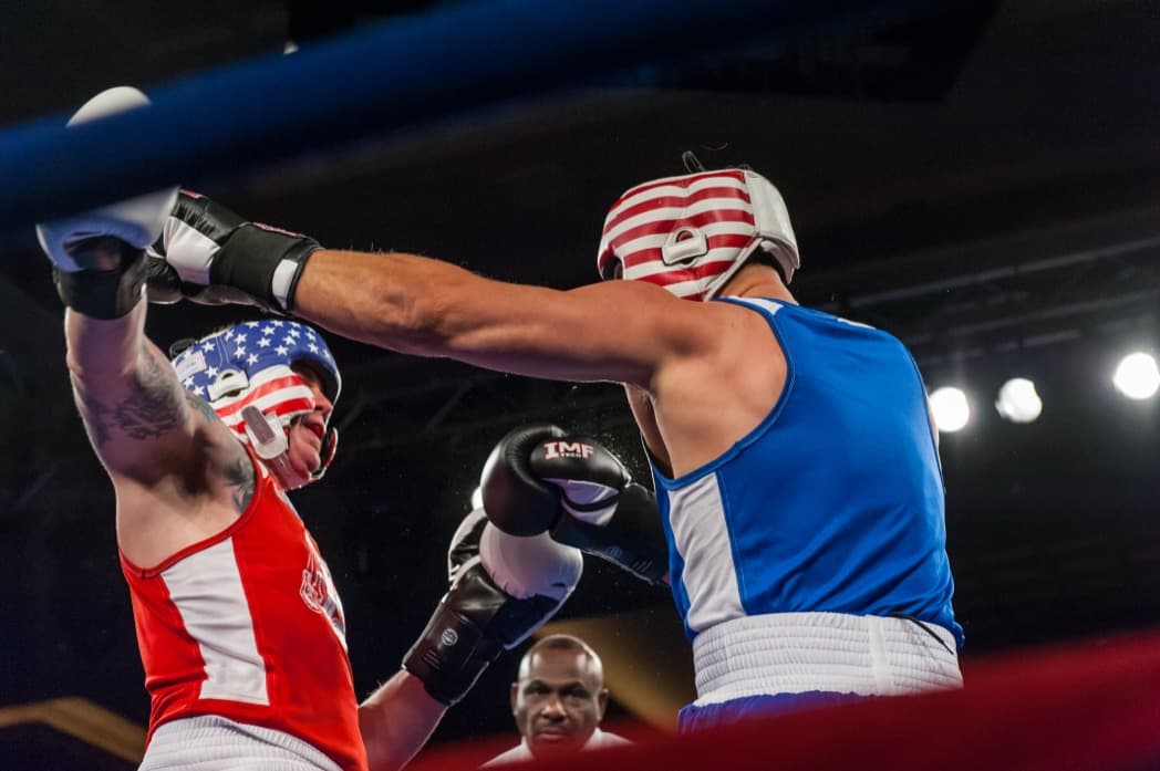 Two amateur boxers exchanging punches in the ring at charity boxing event under dramatic lighting — Cincinnati event photographer K Dalton